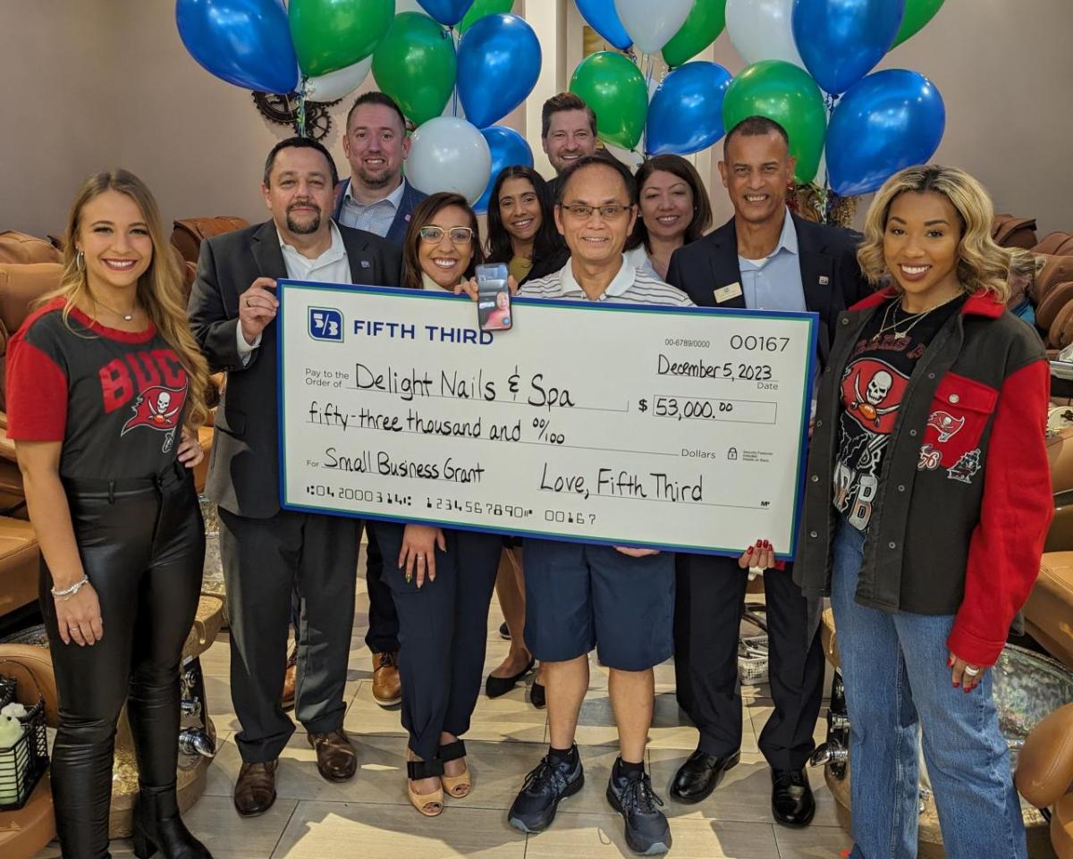 Fifth Third executives were joined by Tampa Bay Bucs cheerleaders to surprise husband and wife owners of Delight Nails & Spa in Orlando with a $53,000 check. As part of the Bank’s “Love, Fifth Third” campaign, Delight Nails & Spa was one of three businesses selected out of 2,200 across Fifth Third’s footprint to win a $53,000 small business grant. " "