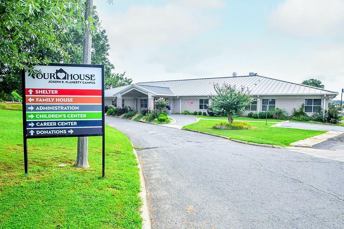 A single-story building "Our House" sign in front with arrows pointing to different buildings.