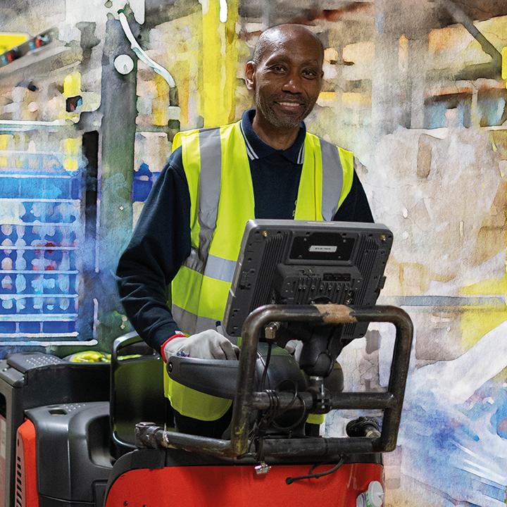 A smiling person in safety vest drivink a forklift.