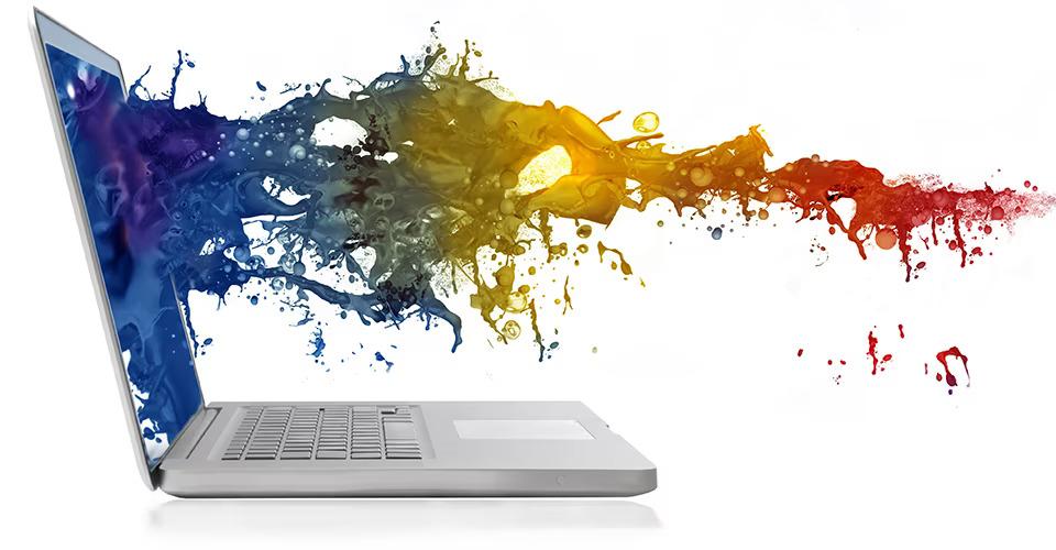 A spray of multi-colored liquid splashing on a laptop screen