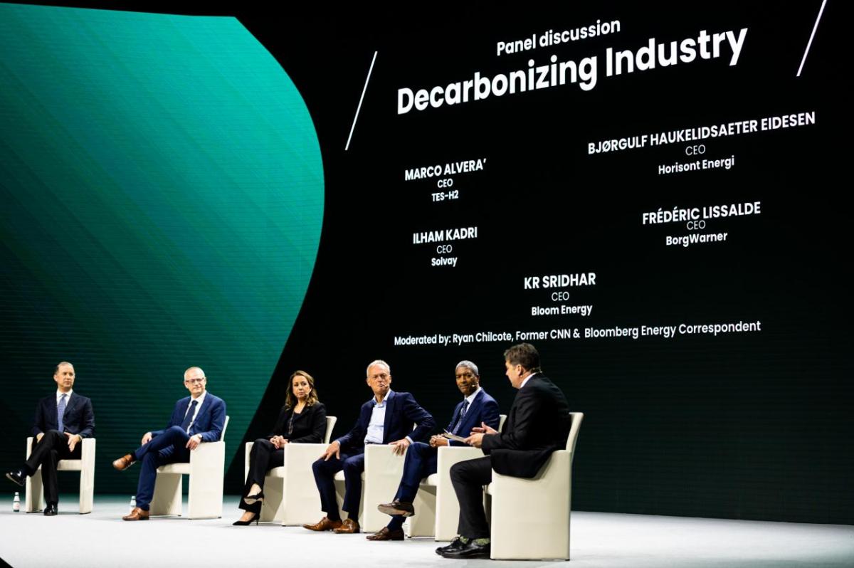 Panel on stage with large screen behind them