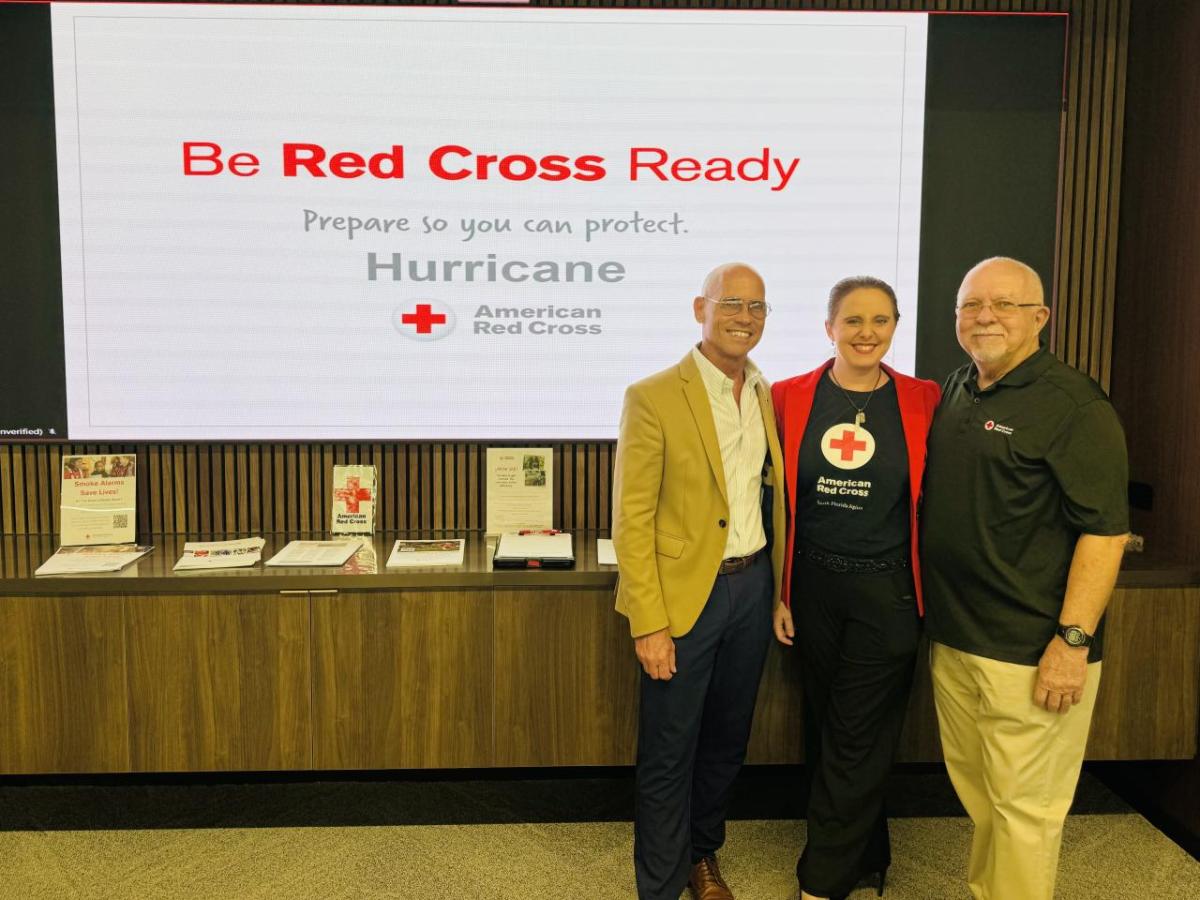 Three people standing in front of a board that reads "Be Red Cross Ready"