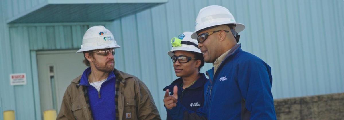 Derrick Smith with two others in hard hats, talking outside a building.