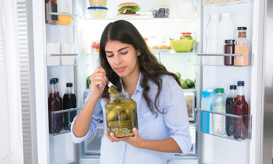 Person leaving fridge open while eating pickles