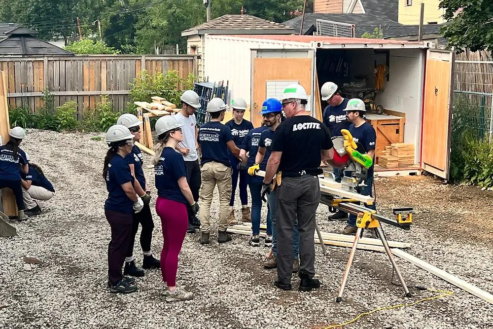 Volunteers outside a home being built, working with wood.