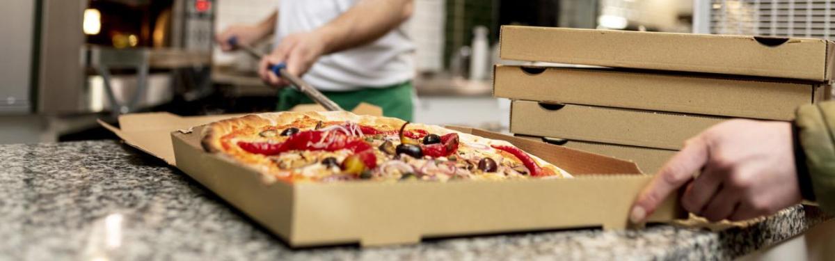 A person placing a pizza in a box.