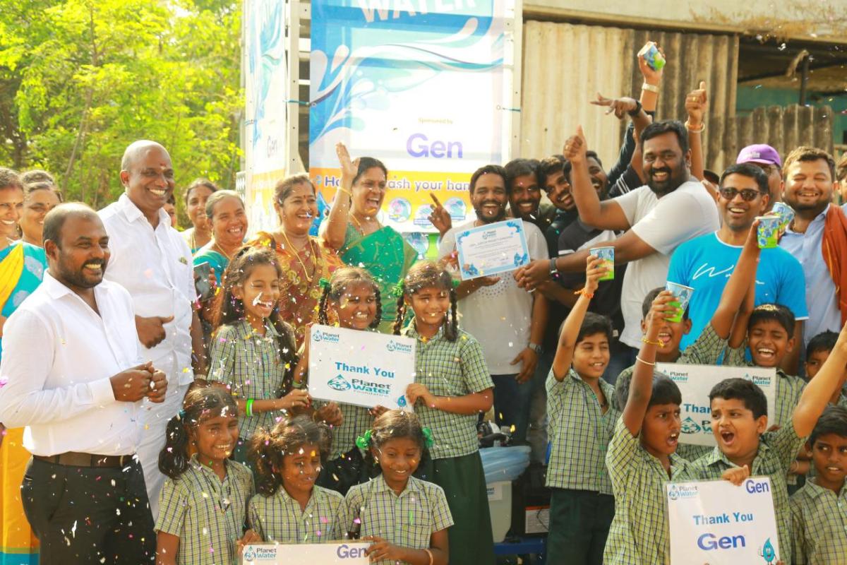 A group of cheering adults and children. Some holding signs "Thank you Gen" and "Thank you Planet Water".