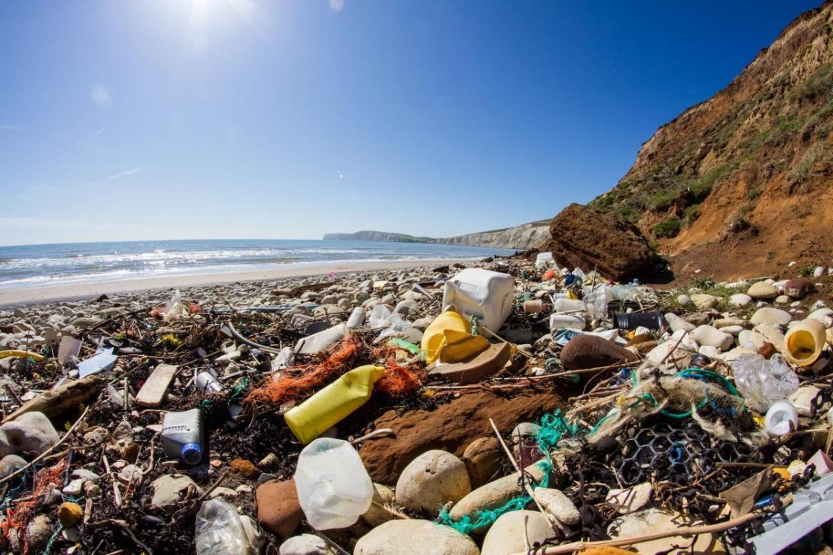 Plastic garbage on a beach, waves in the distance.