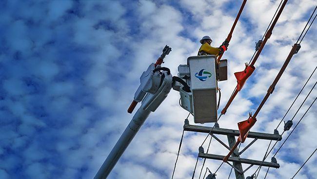 A line worker in a bucket truck working on a power line