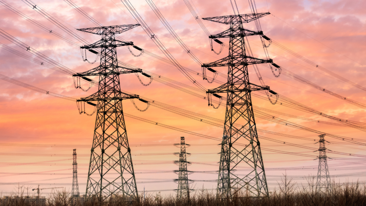 Tall power lines, a sunset sky behind.