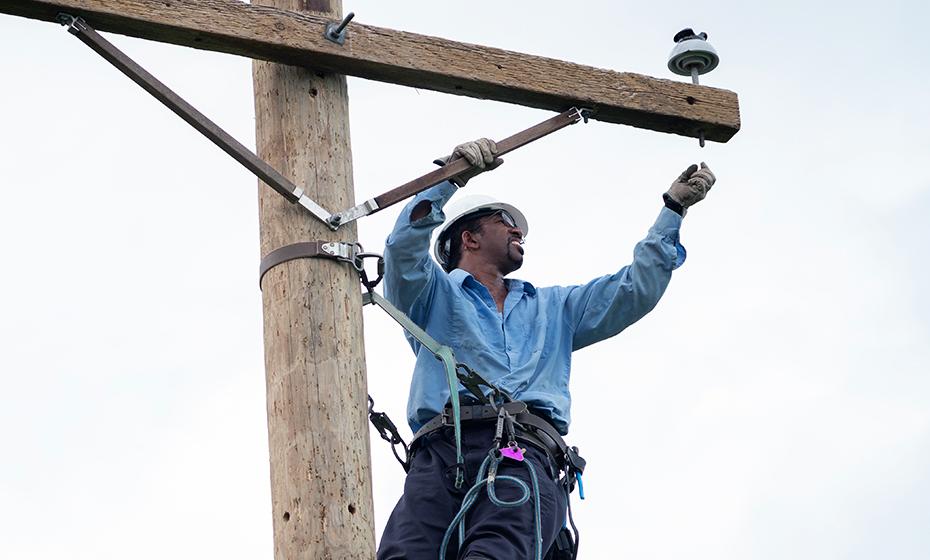 A person high on on an electrical pole making repairs.