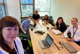 A group of people at a long office table looking at the camera.