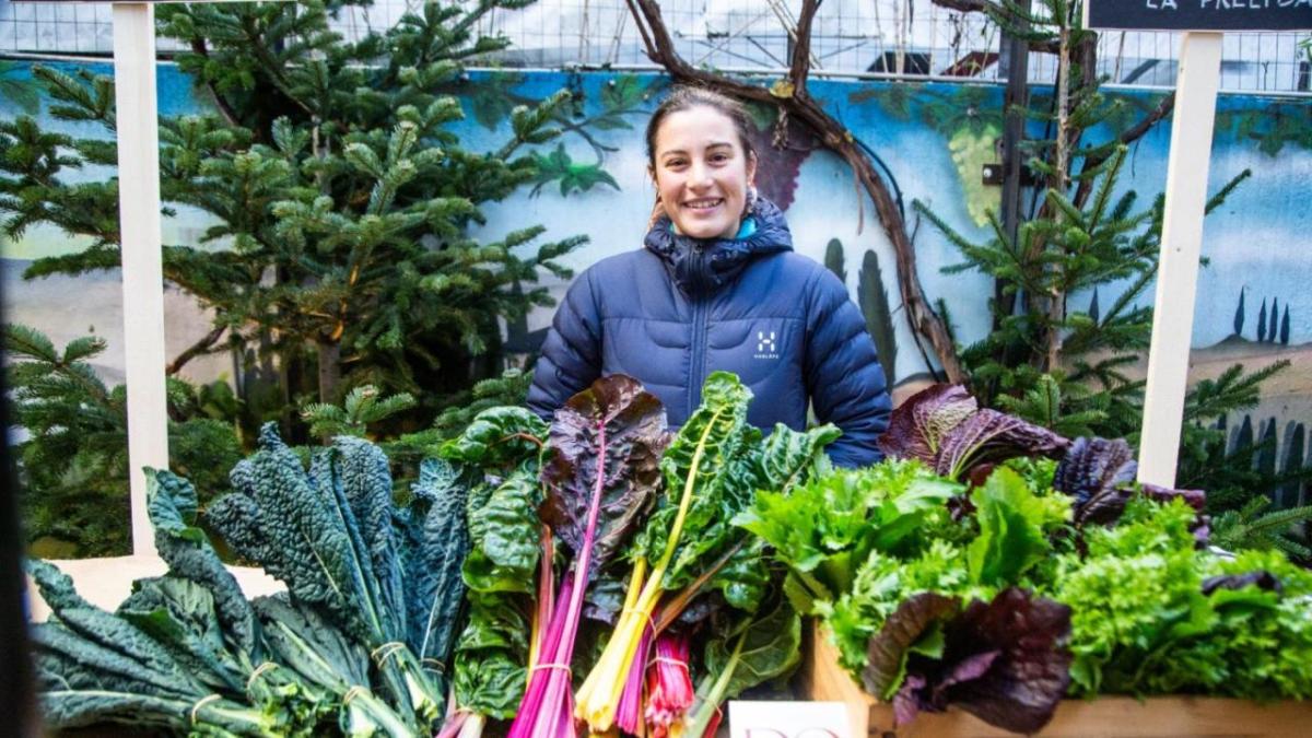 A person behind a table full of fresh produce