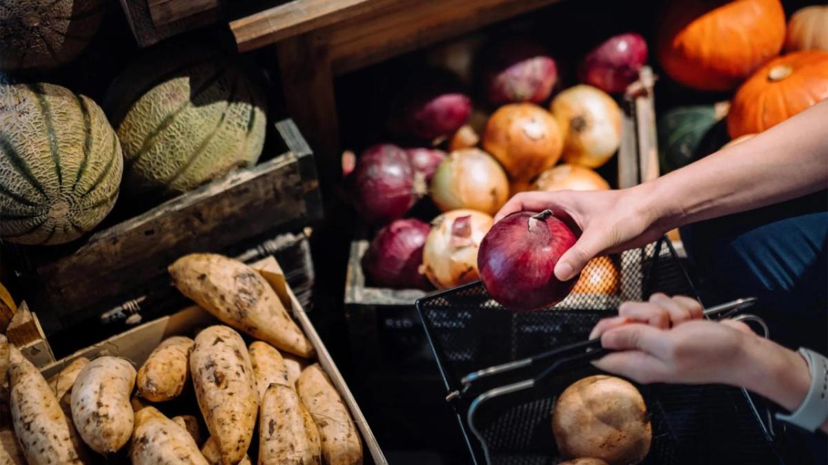 A person holding produce to put in a basket.