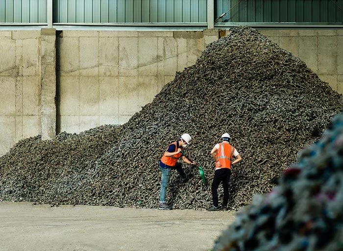 Two workers next to a pile of material