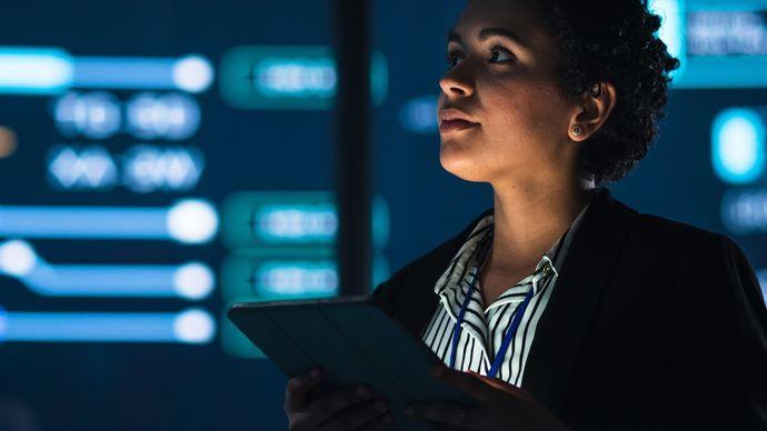 A person looking up in a dark room with digital screens on the walls.