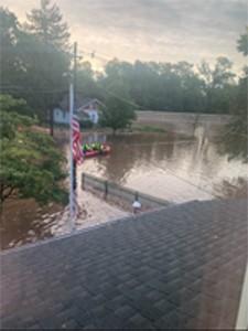 Homes flooded by recent storms. Flag pole is shown with flood waters rising up.