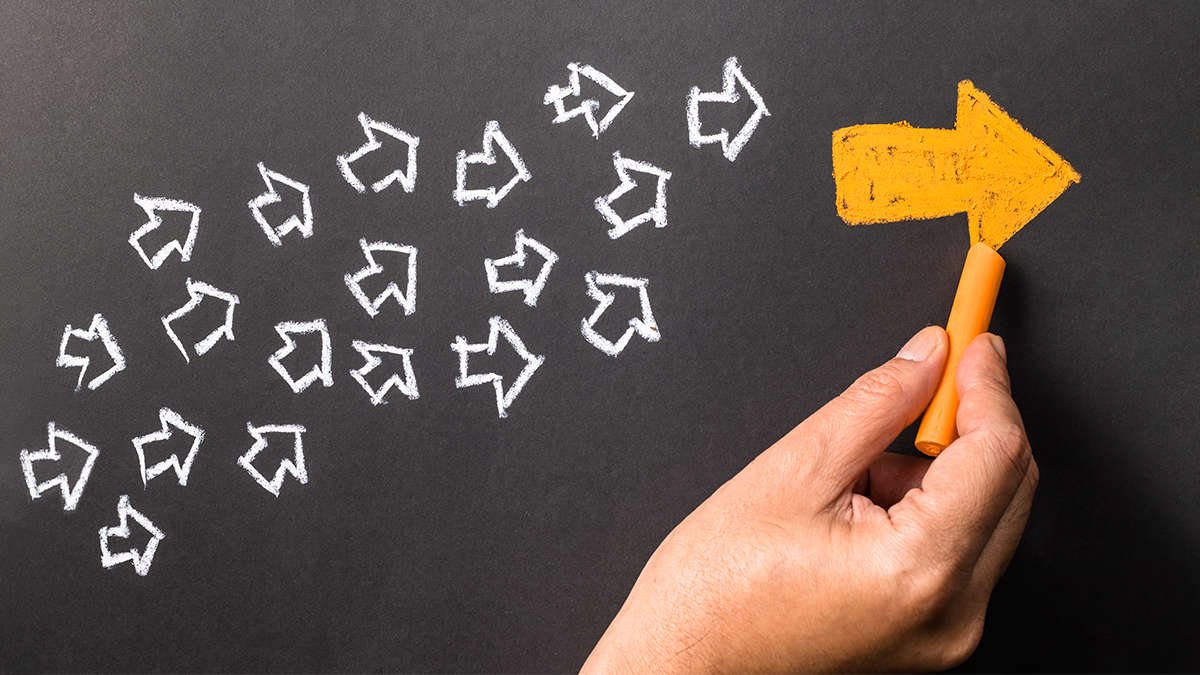 Hand drawing on a chalkboard. A group of small white arrows pointing to a larger yellow arrow.