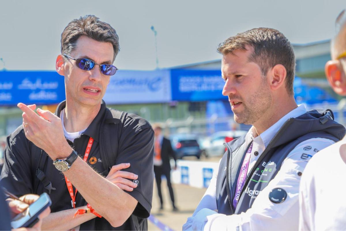 Two people talking on a race track.