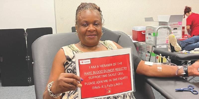 a person donating blood holding a sign "I'm registered as a rare blood donor"