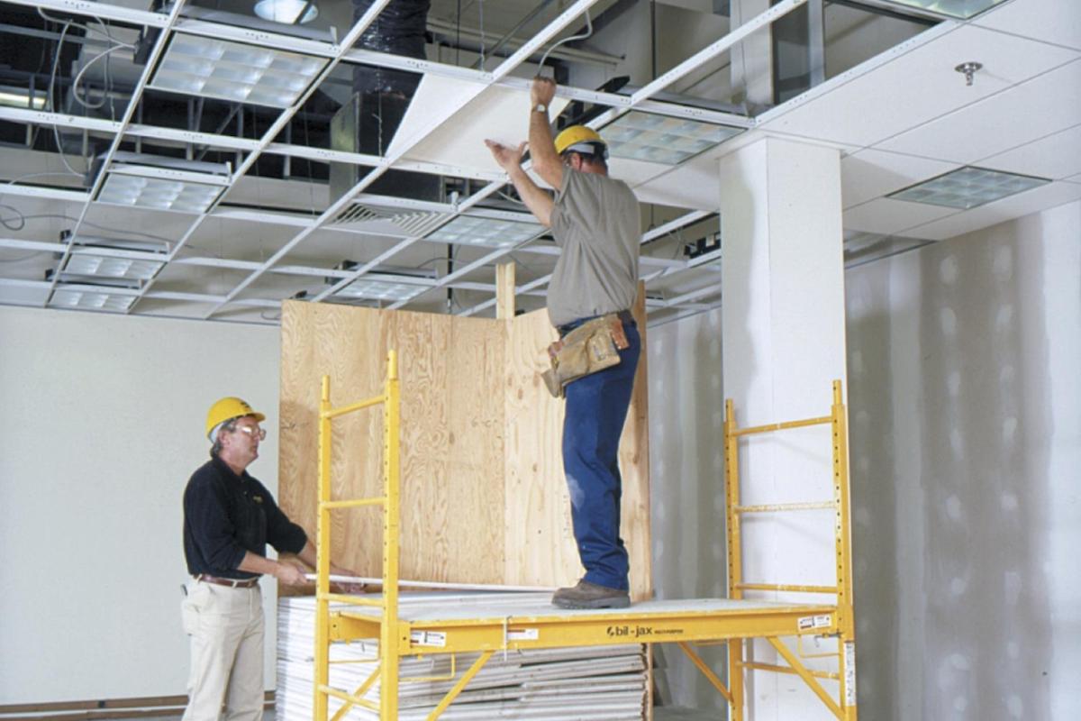 two construction workers putting in a drop ceiling
