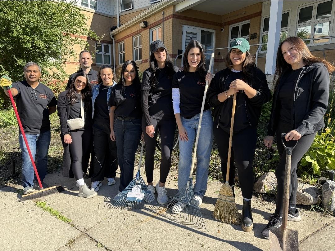 A group standing together outside a building with gardening and cleaning tools