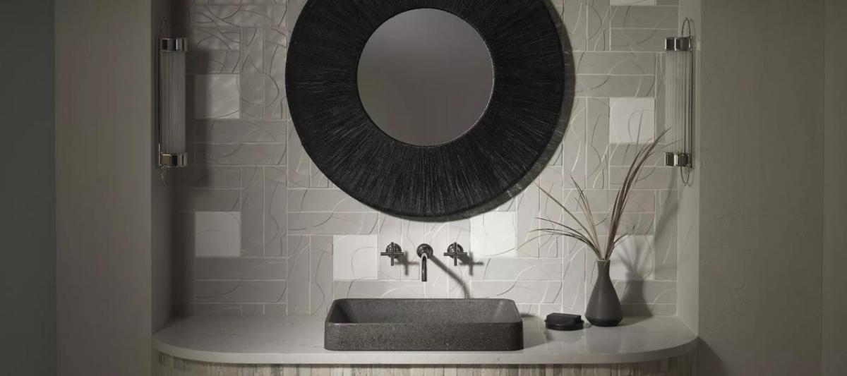A black and white vanity, sink and mirror. A plant to one side.