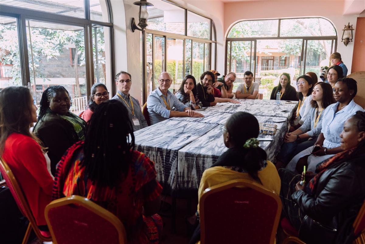 A large group of people indoors around a rectangular table