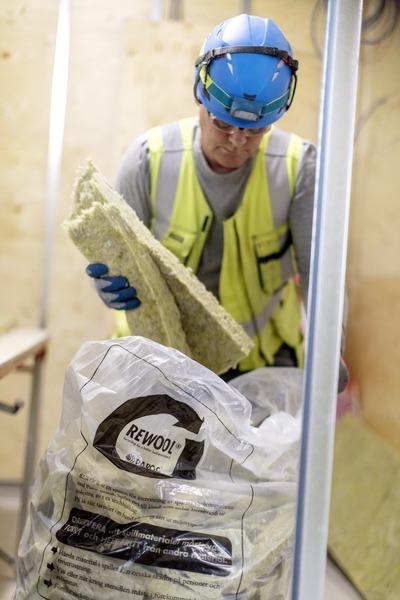 A person putting pieces of insulation in a bag.