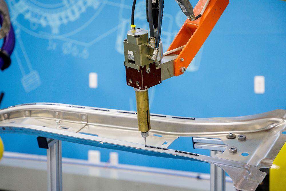 Close-up robotic application of structural adhesive on car body