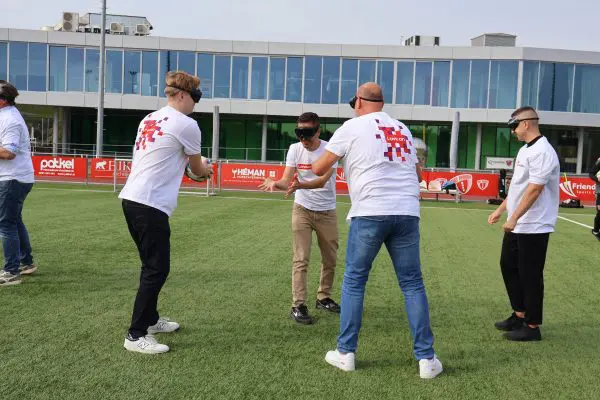 Blindfolded people throwing a ball to each other on a field