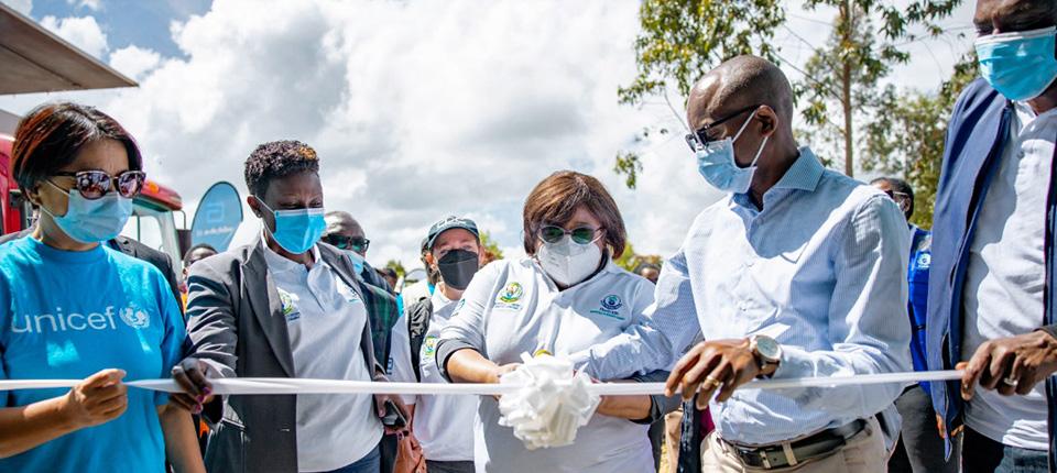 a group of people cut a white ribbon, all wearing medical masks
