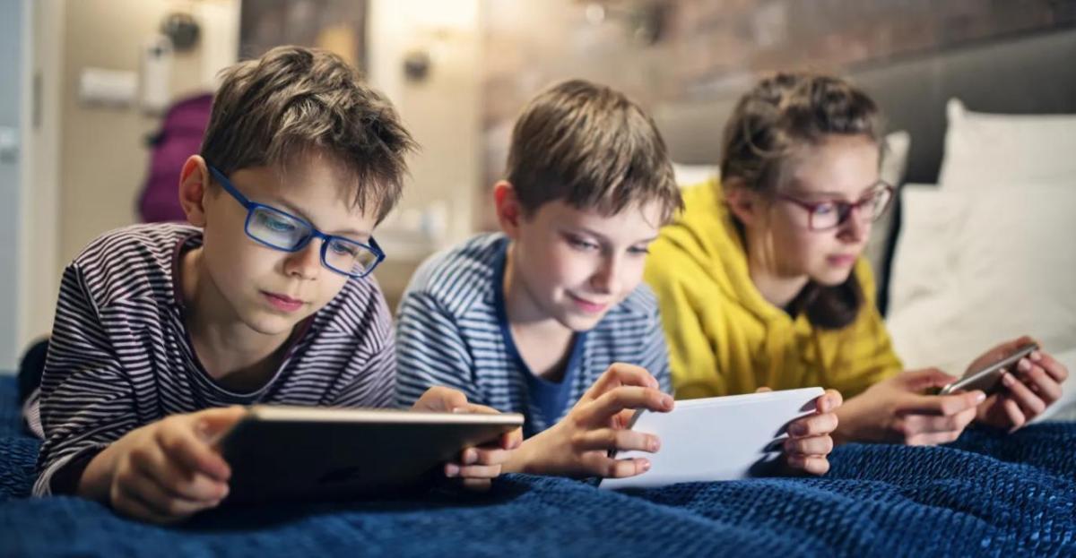 Three children using electronic devices.