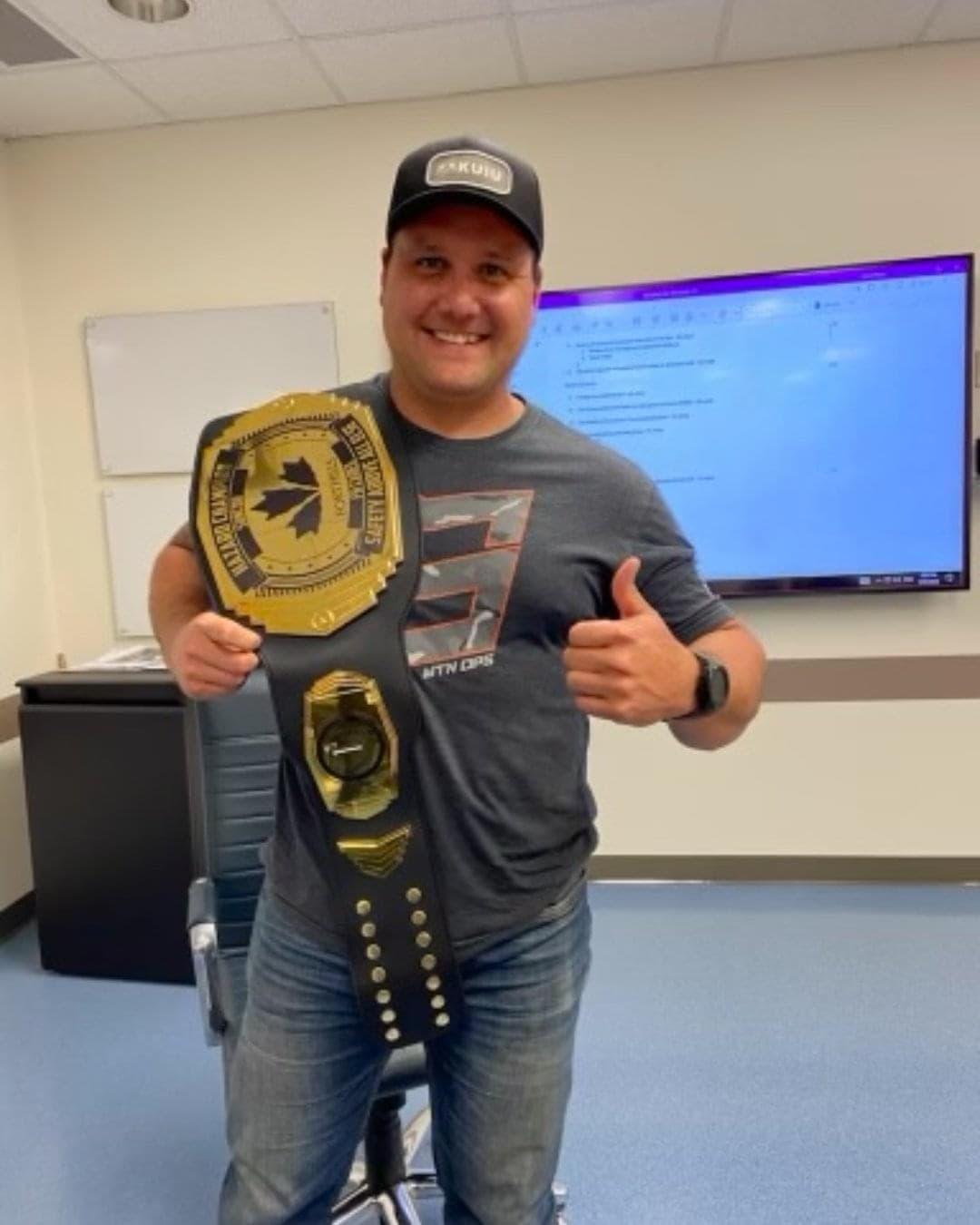 JM Bilodeau posing with a large championship belt over his shoulder.