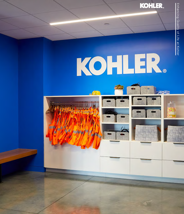 Kohler in white on a blue wall. Cabinets with drawers and a rack of orange safety vests.