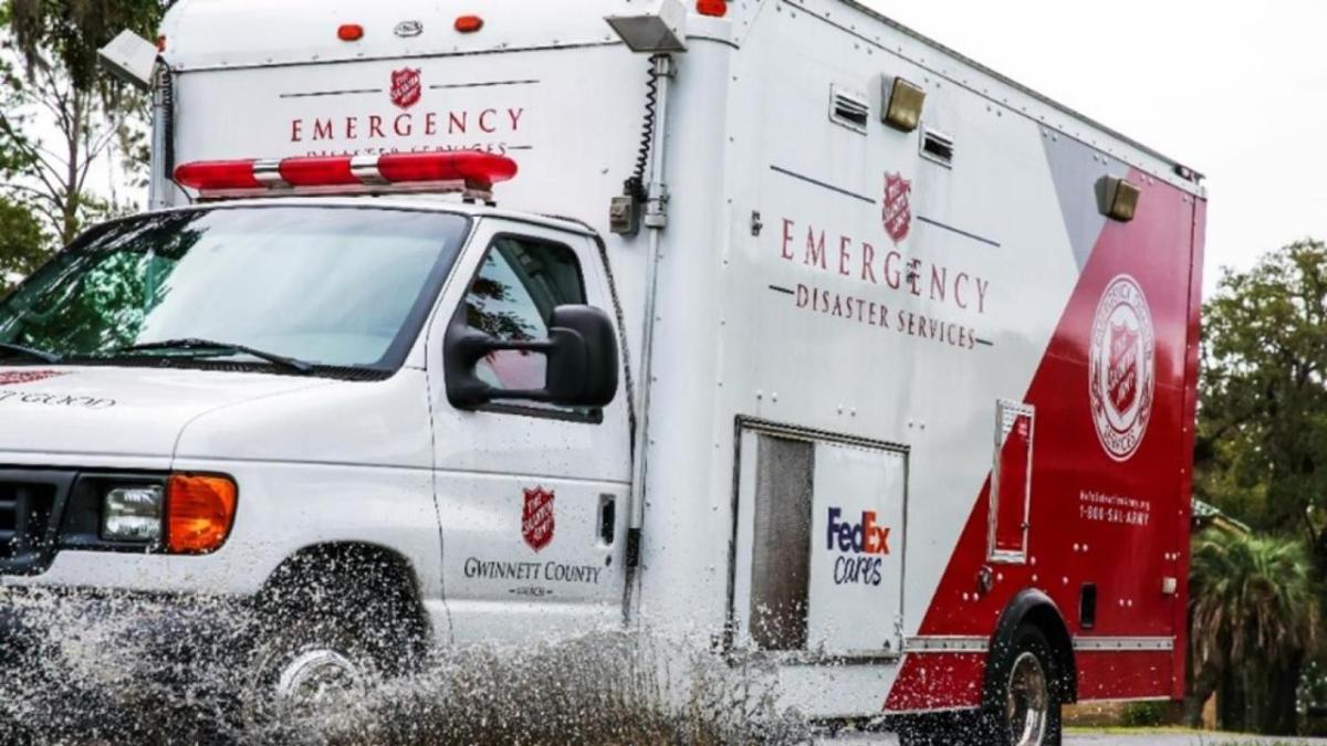 A box truck going through a puddle. Salvation Army and FedEx logos on the sides.