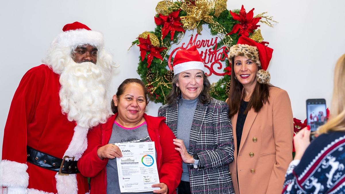 A recipient posed with Santa and Entergy employees.