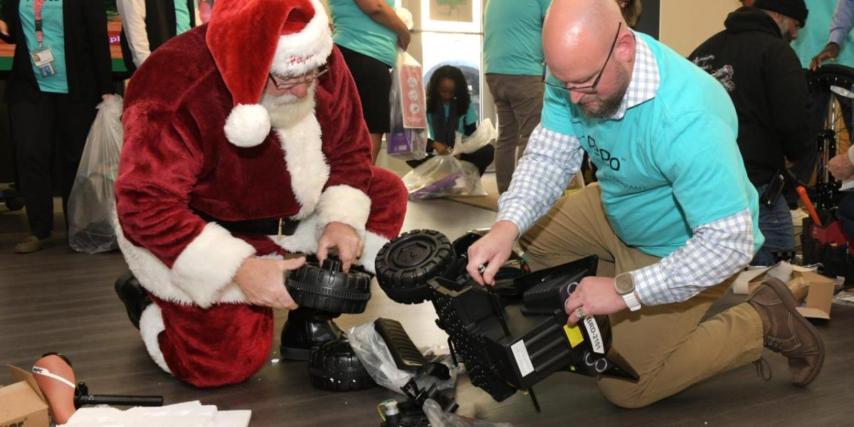 Volunteer helping santa assemble a toy.