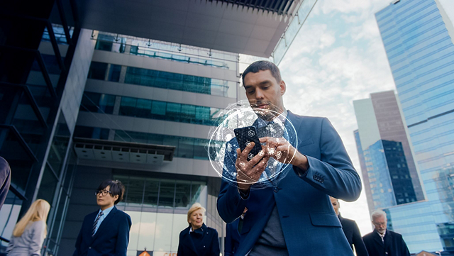 A person outside tall buildings using a cell phone.