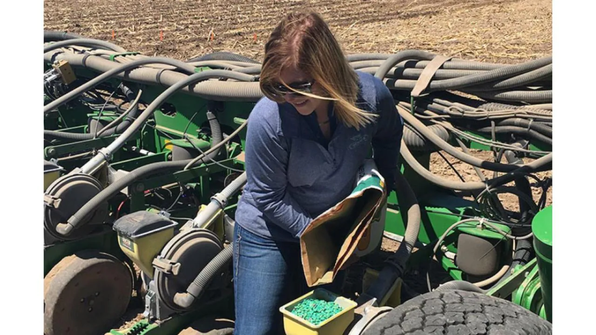 A person loading seed hoppers on a large agricultural machine