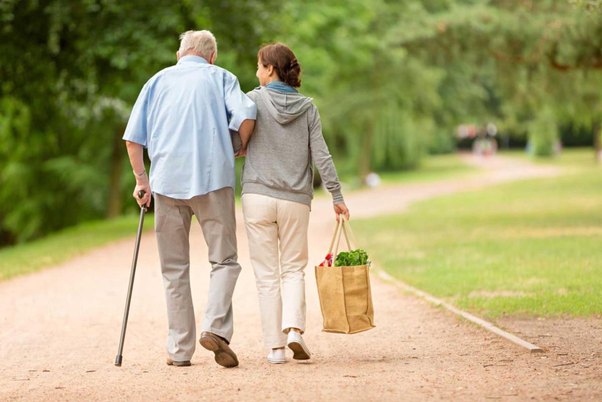 two senior citizens walking arm in arm