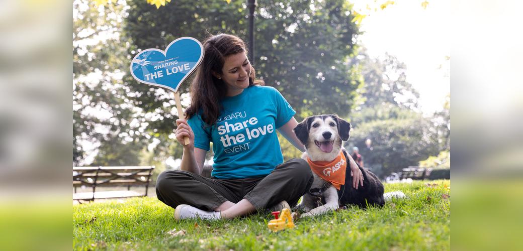Person wearing "Subaru share the love event" shirt sitting next to a dog