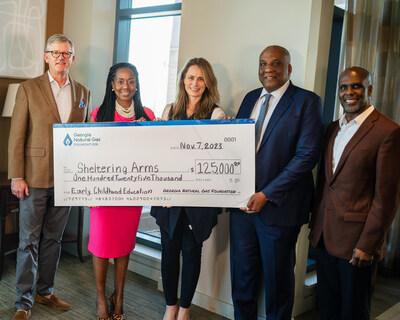 Five people posed with a large check made to Sheltering Arms.