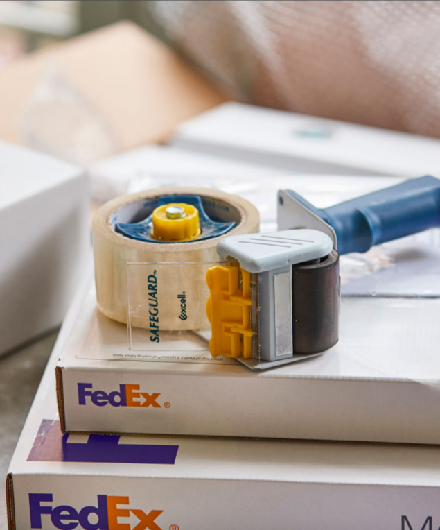 a stack of FedEx boxes and a tape gun on top of them