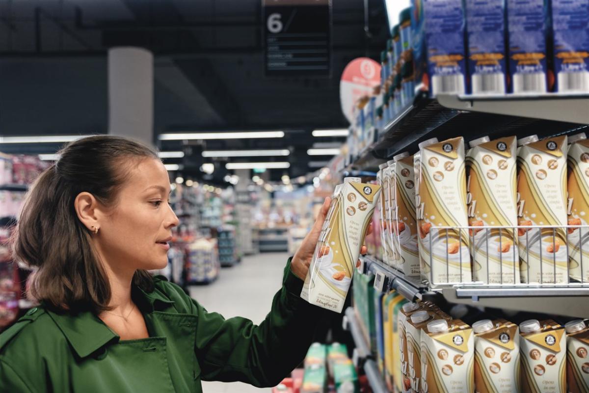 A person in a grocery store, selecting a box from a shelf.