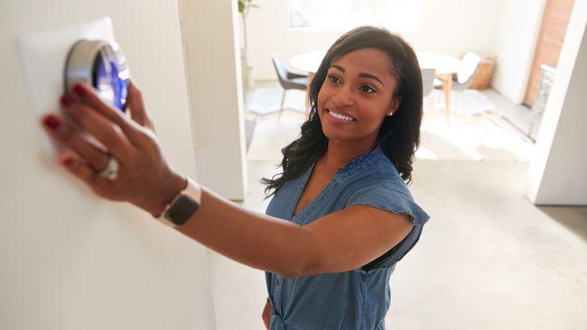 Person turning a thermostat