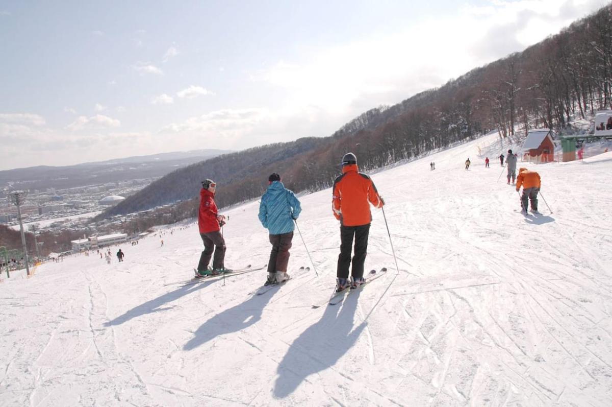 Two people getting a ski lesson from a third on a snow hill.