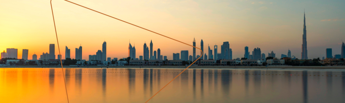 A city skyline at sunset, a body of water in front.