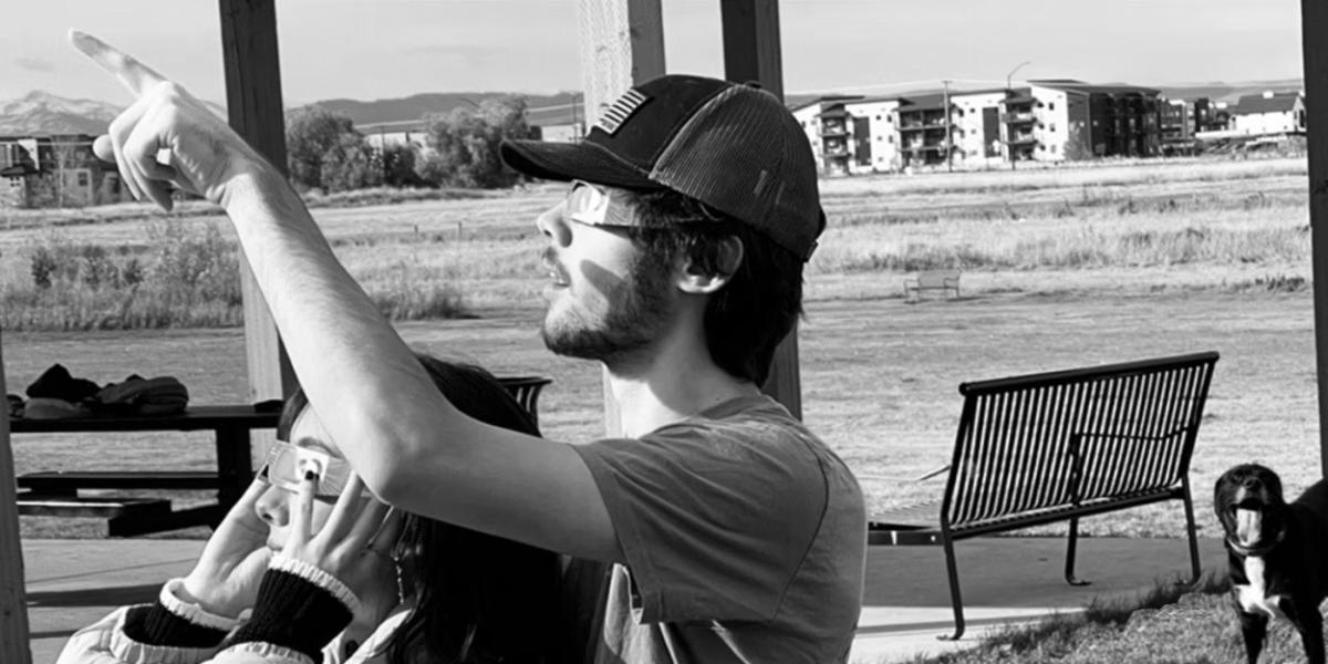 A black and white photo of two people watching an eclipse.