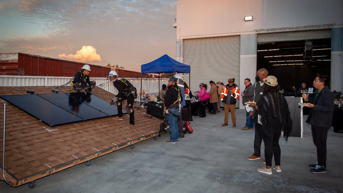 At the CTTC launch earlier this month, Daniel Montero (top), a solar installation supervisor, and Wilton Williams (bottom), a SolarCorps Construction Fellow and current trainee, show off the mock solar roof. Mock solar roof installation